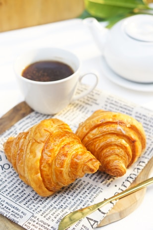 Bright morning sunlight streaming onto a table with a steaming mug of coffee and freshly baked croissants wrapped in a hint of MacGregor tartan cloth.