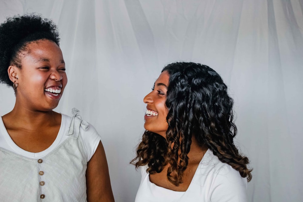 two women laughing and standing next to each other