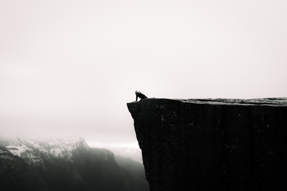 a person sitting on top of a cliff