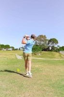 Golfer wearing a sleek Nike polo and cap, mid-swing on a sunny course