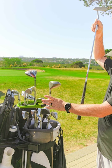 A close-up of a golfer selecting a club from an organized golf bag on a sunny course.