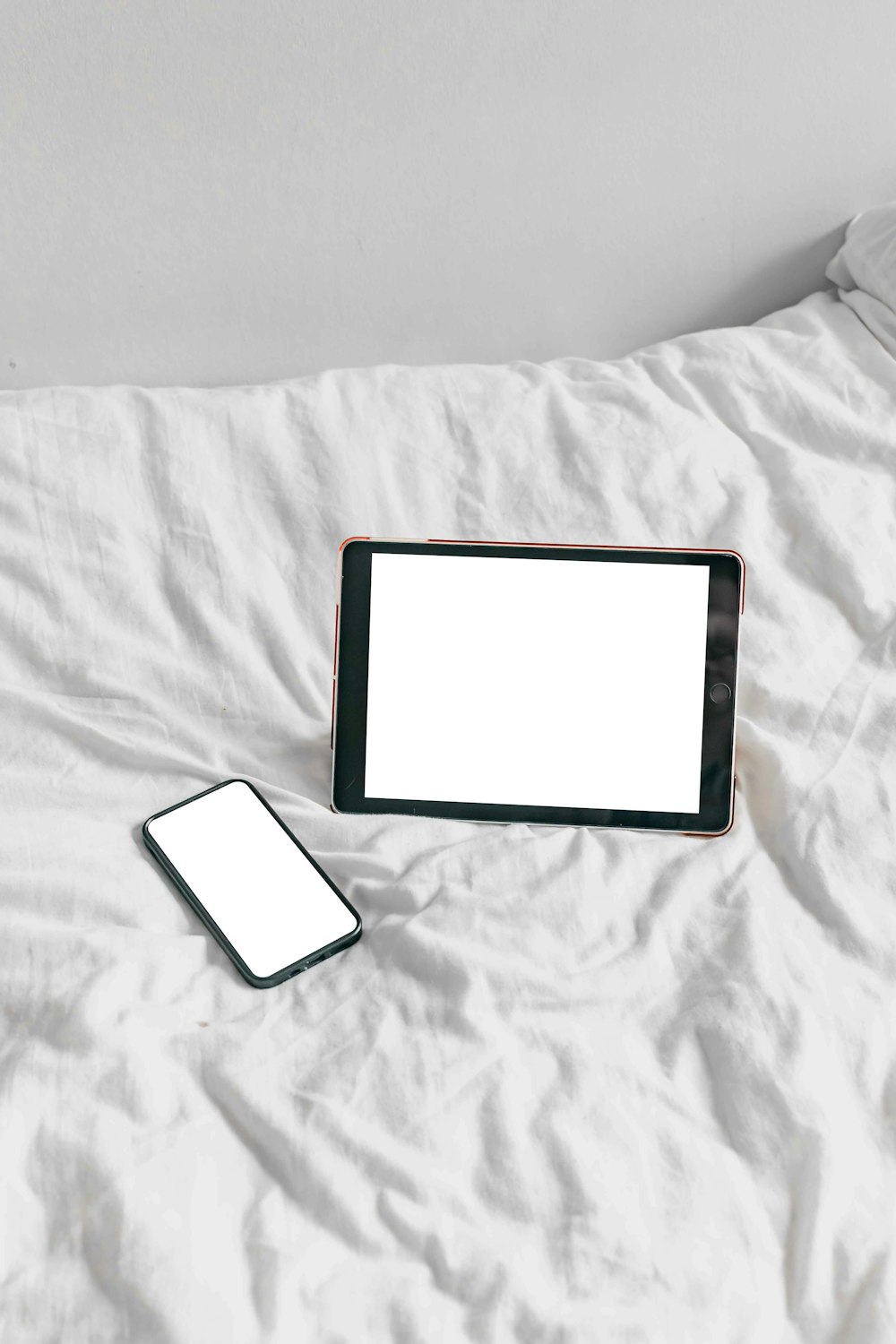 a tablet and a cell phone on a bed