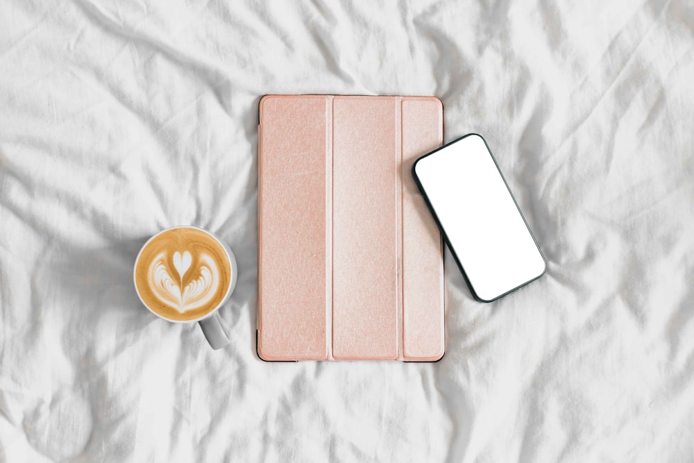 a cup of coffee and a tablet on a bed