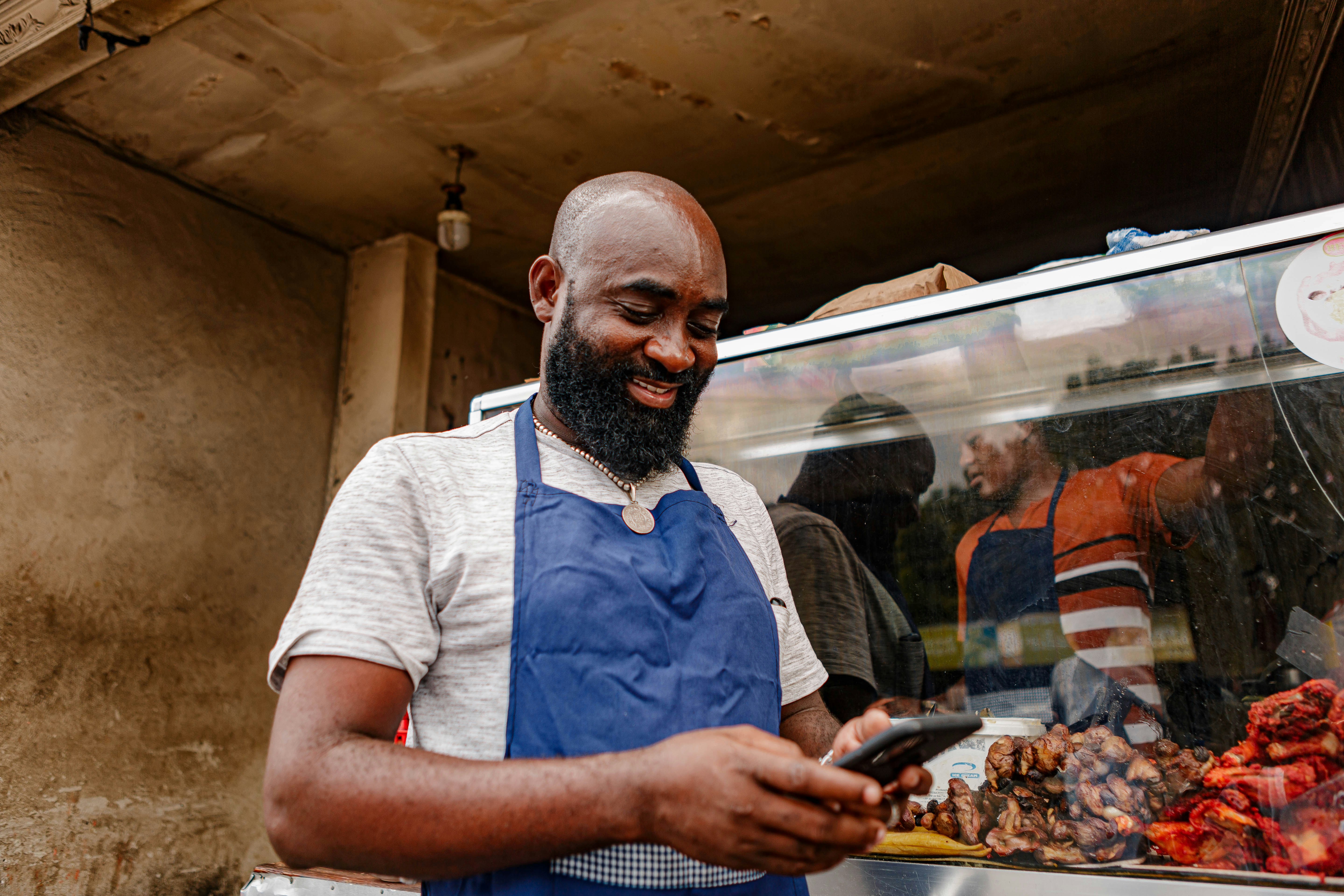 a man in an apron looking at a cell phone