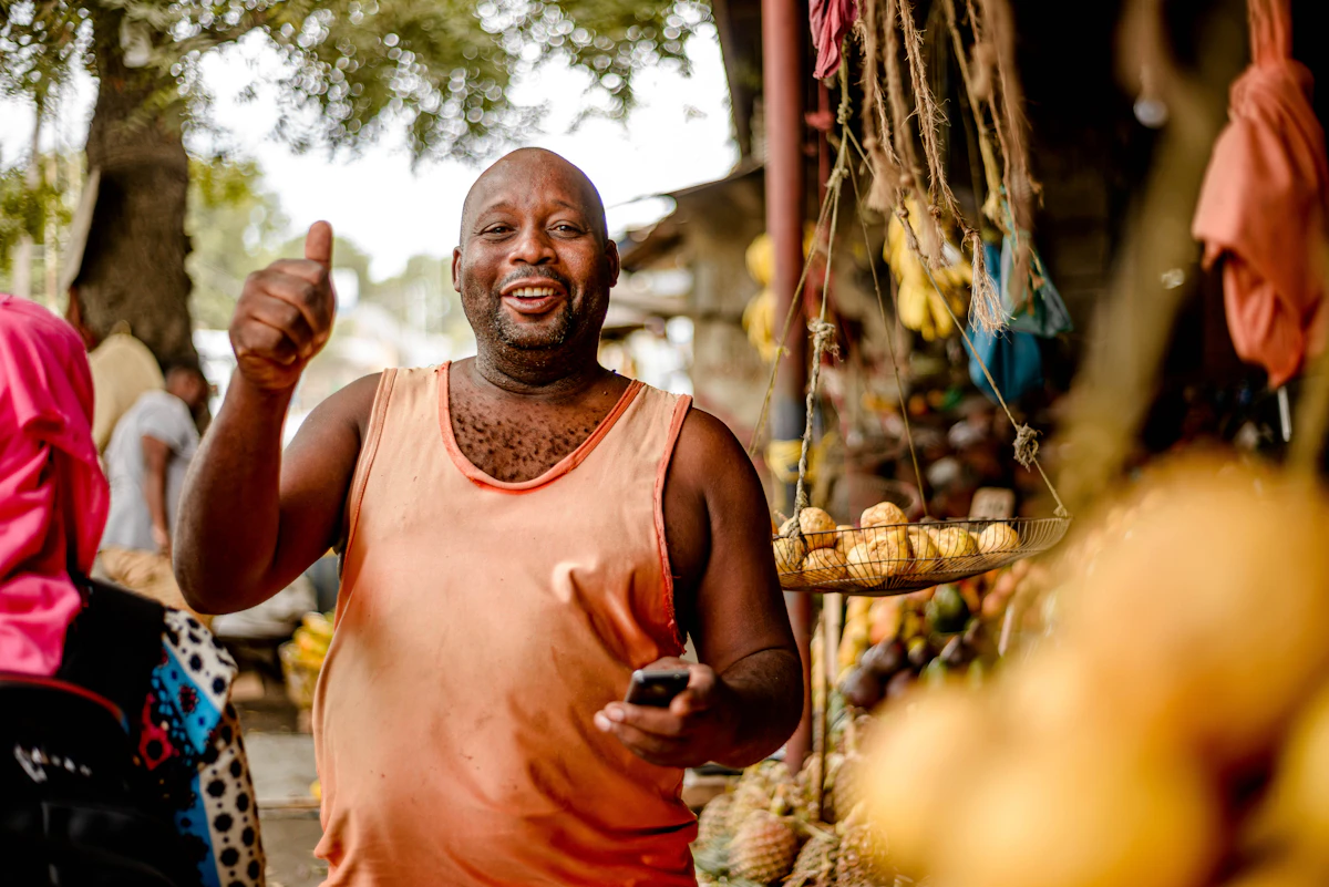 Commercant africain devant son etal de fruits