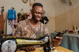 a man smiles as he uses a sewing machine