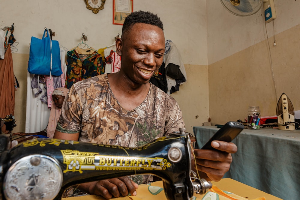a man smiles as he uses a sewing machine