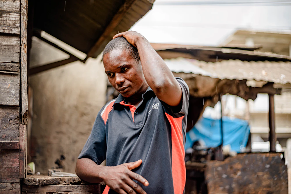 A Ghanaian man with his hand on his head, looking concerned about money