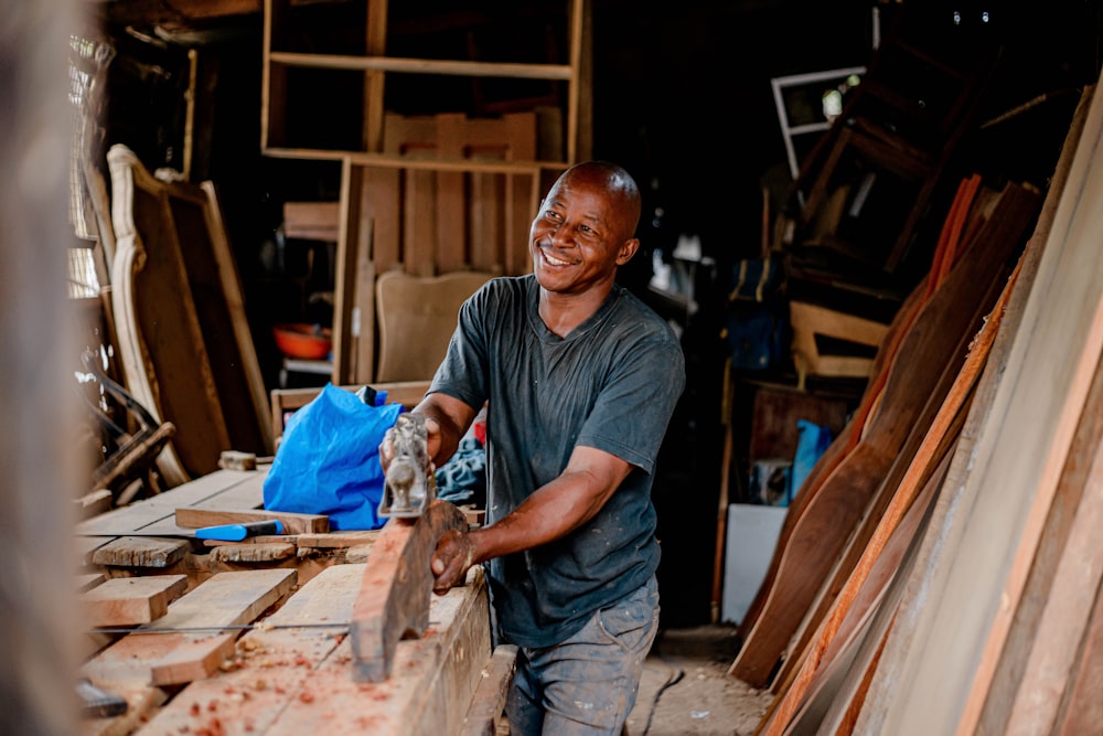 a man smiles as he works on a piece of wood