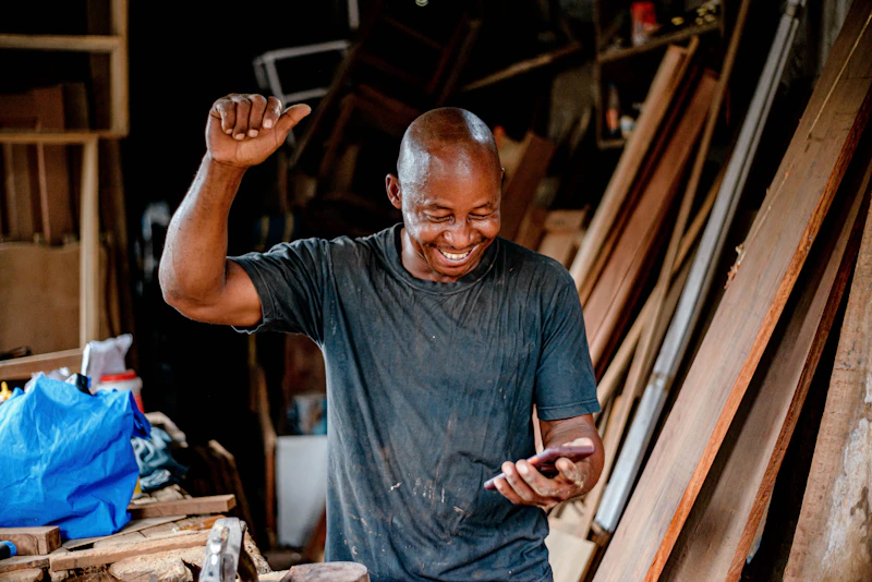 A small business owner smiling while checking messages on his phone
