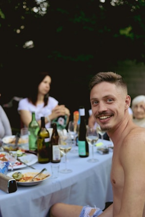 a shirtless man sitting at a table with a plate of food