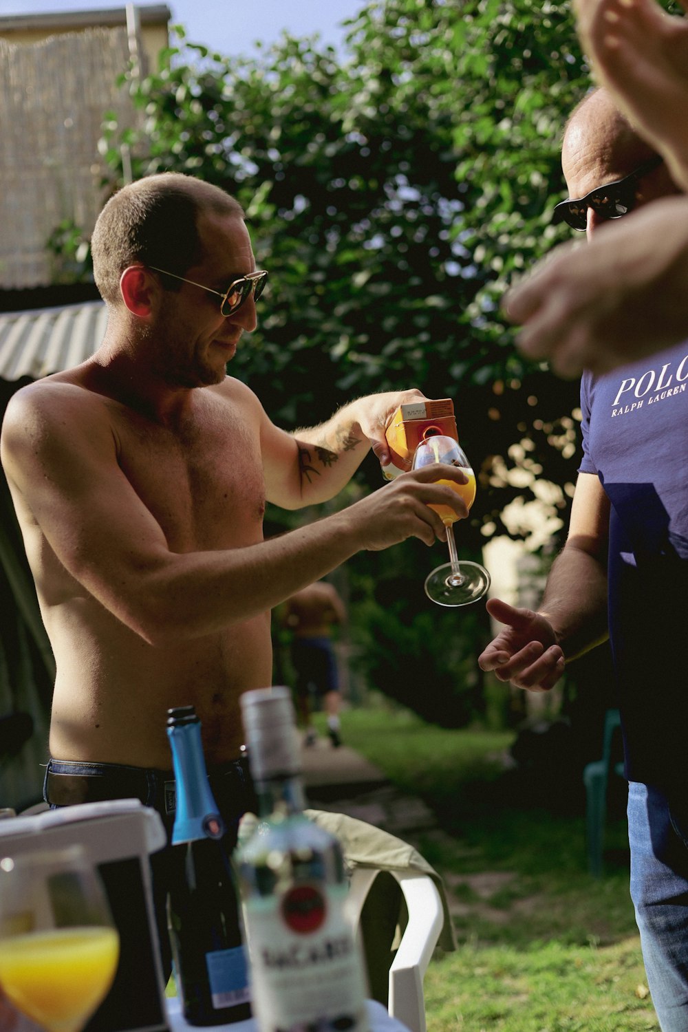 a shirtless man holding a glass of wine