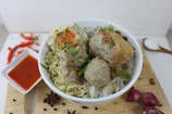 A colorful plate of bakso meatballs served with noodles and spicy chili sauce.