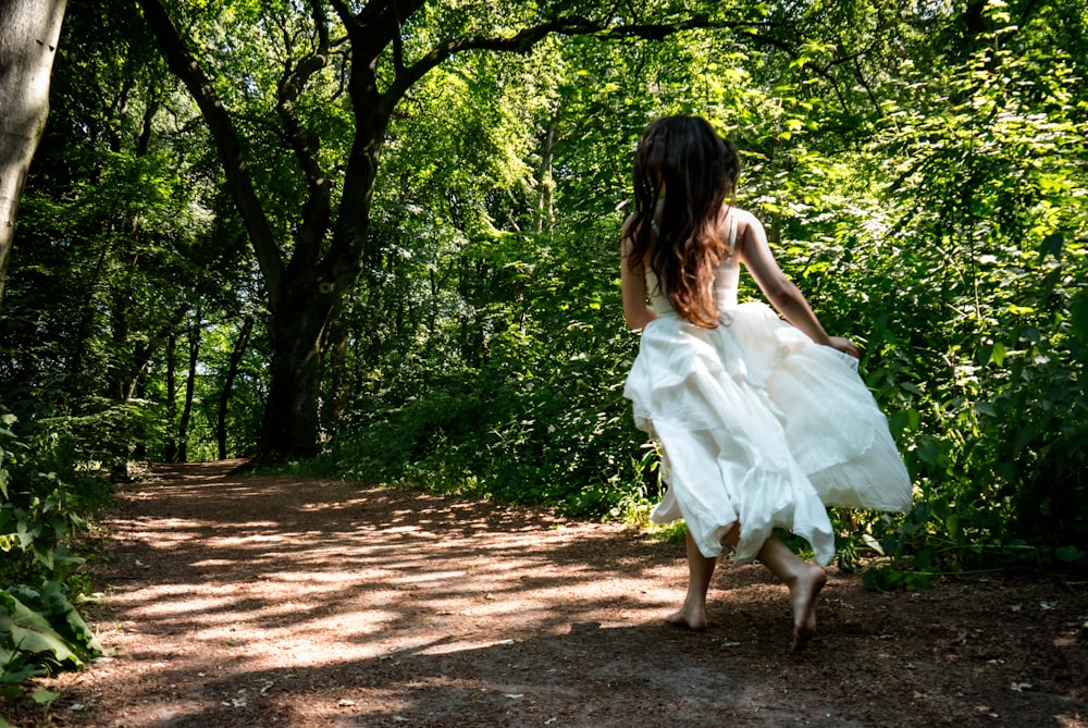 a woman in a white dress is walking down a path