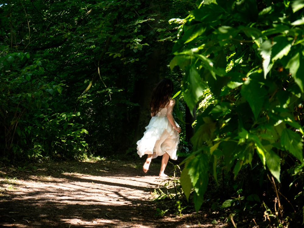 a woman in a white dress is running down a path