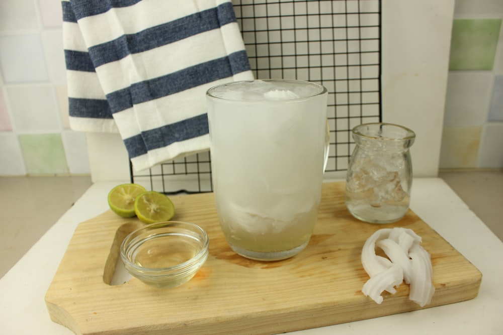 a wooden cutting board topped with a glass of water