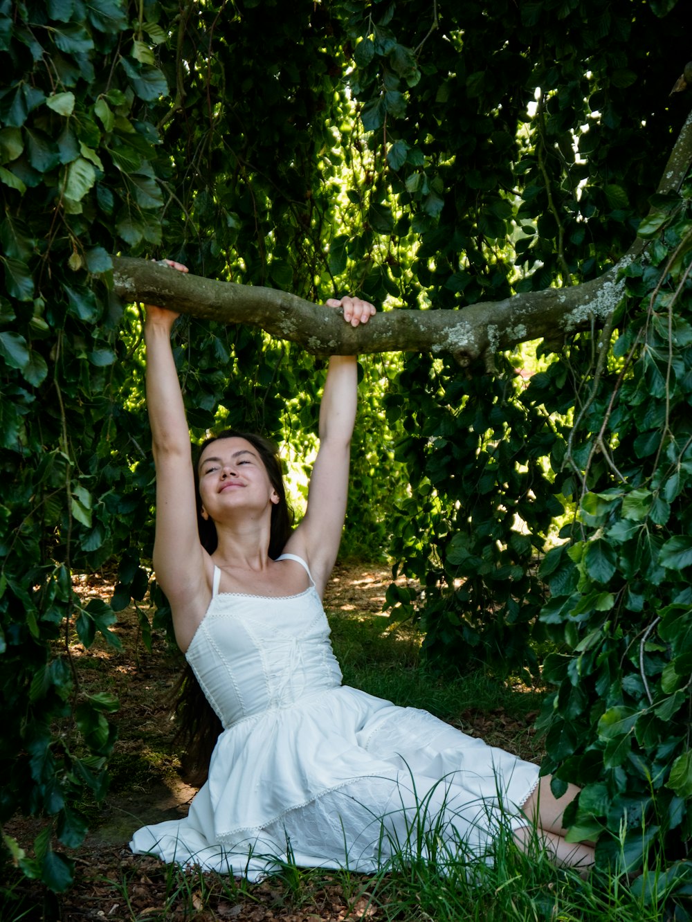 a woman in a white dress holds a branch above her head