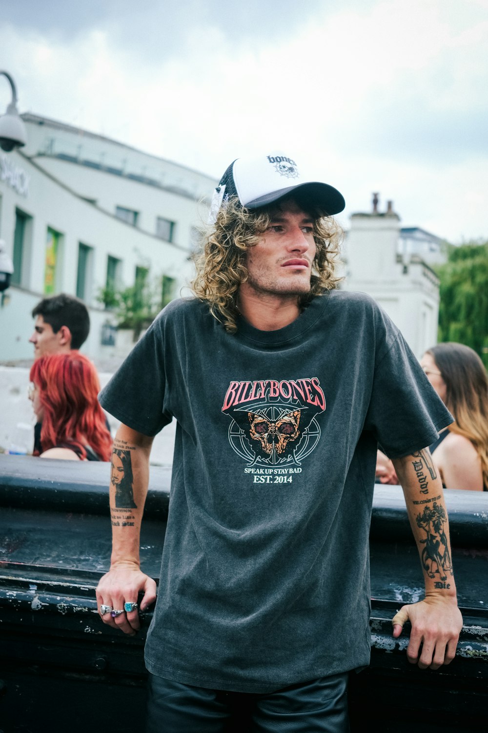 a man with long hair and tattoos standing in front of a truck