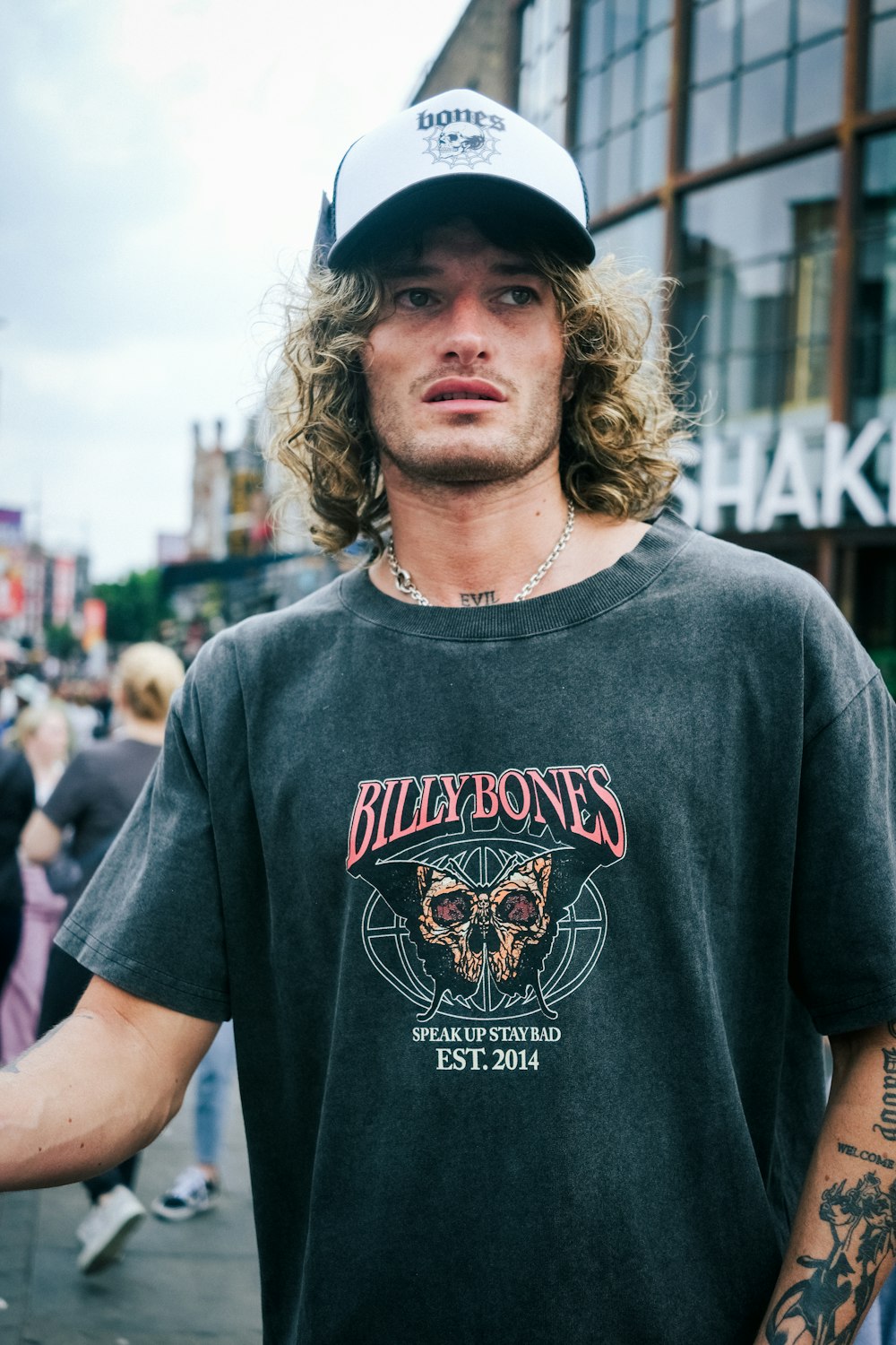 a man with long hair wearing a black shirt and a hat