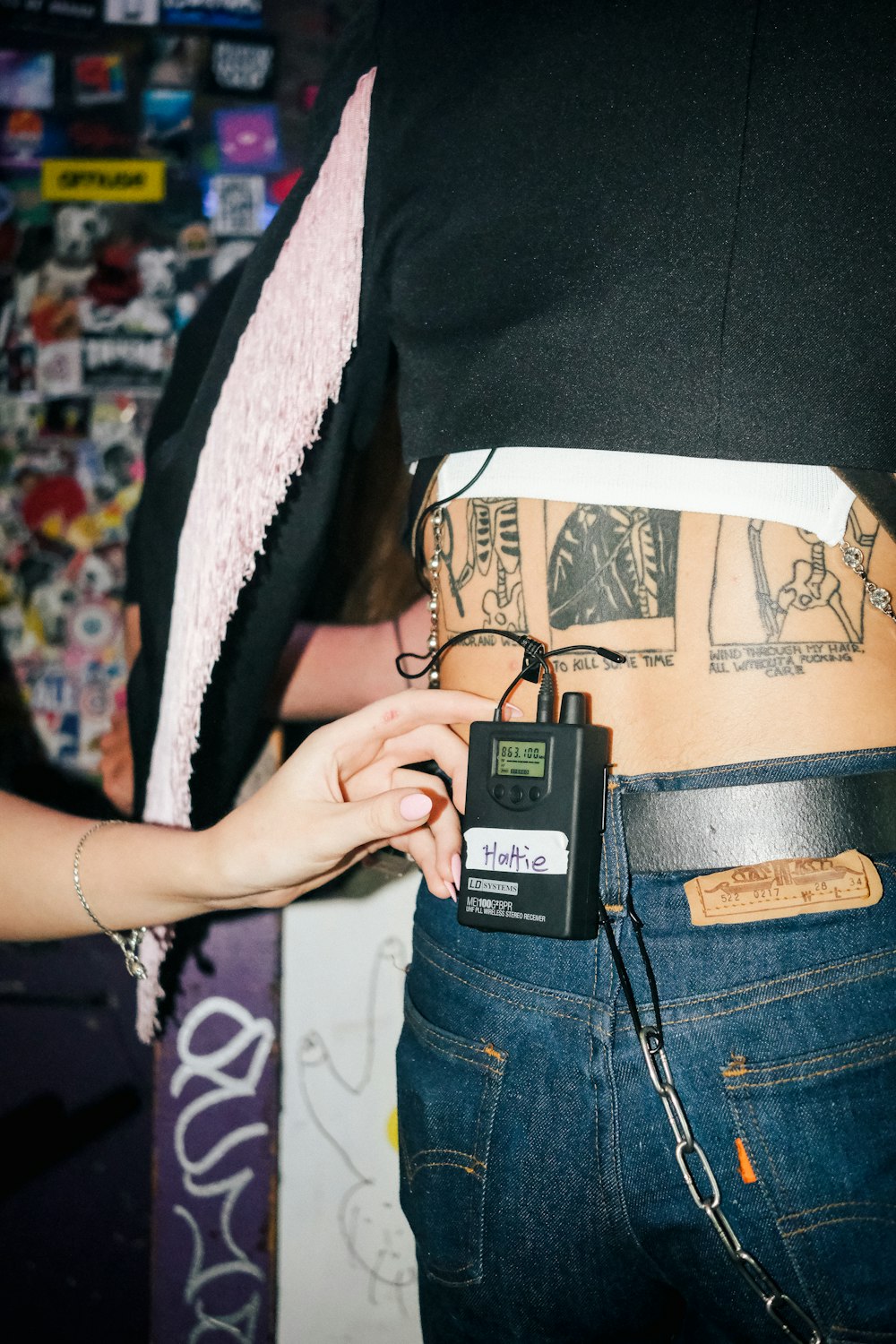 a person with tattoos on their stomach holding a cell phone