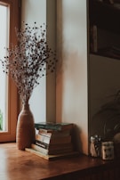 A rustic wooden coffee table adorned with a stack of vintage books, a ceramic mug, and a small bouquet of dried flowers.