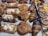 A variety of freshly baked pastries are displayed on trays, including croissants, chocolate-dipped palmiers, almond-topped pastries, and spiral cinnamon rolls. Price tags indicate the cost of some items.