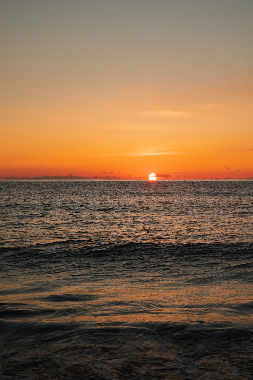 a sunset over the ocean with a boat in the distance