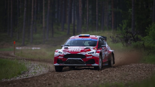 Team 988 rally car speeding through a rugged forest trail kicking up dust.