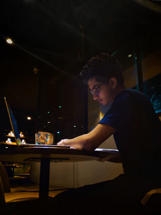 A focused young professional working late at a desk with a cup of Mindfuel beside their laptop.