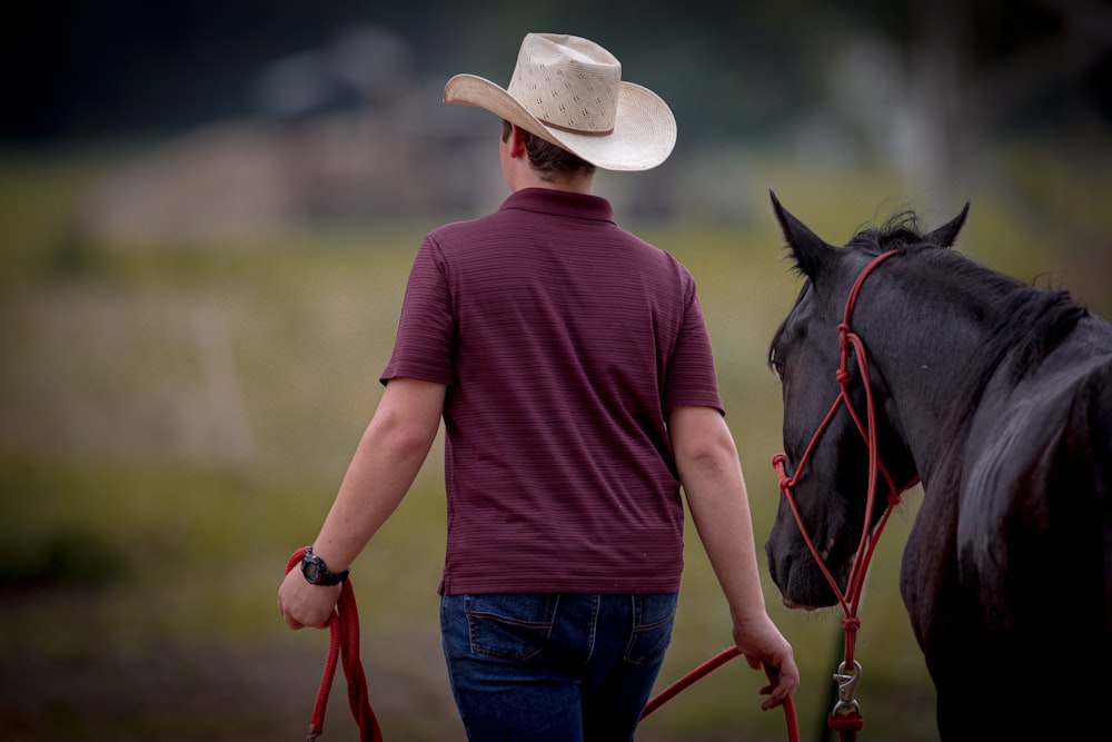 Un homme coiffé d’un chapeau de cow-boy promenant un cheval