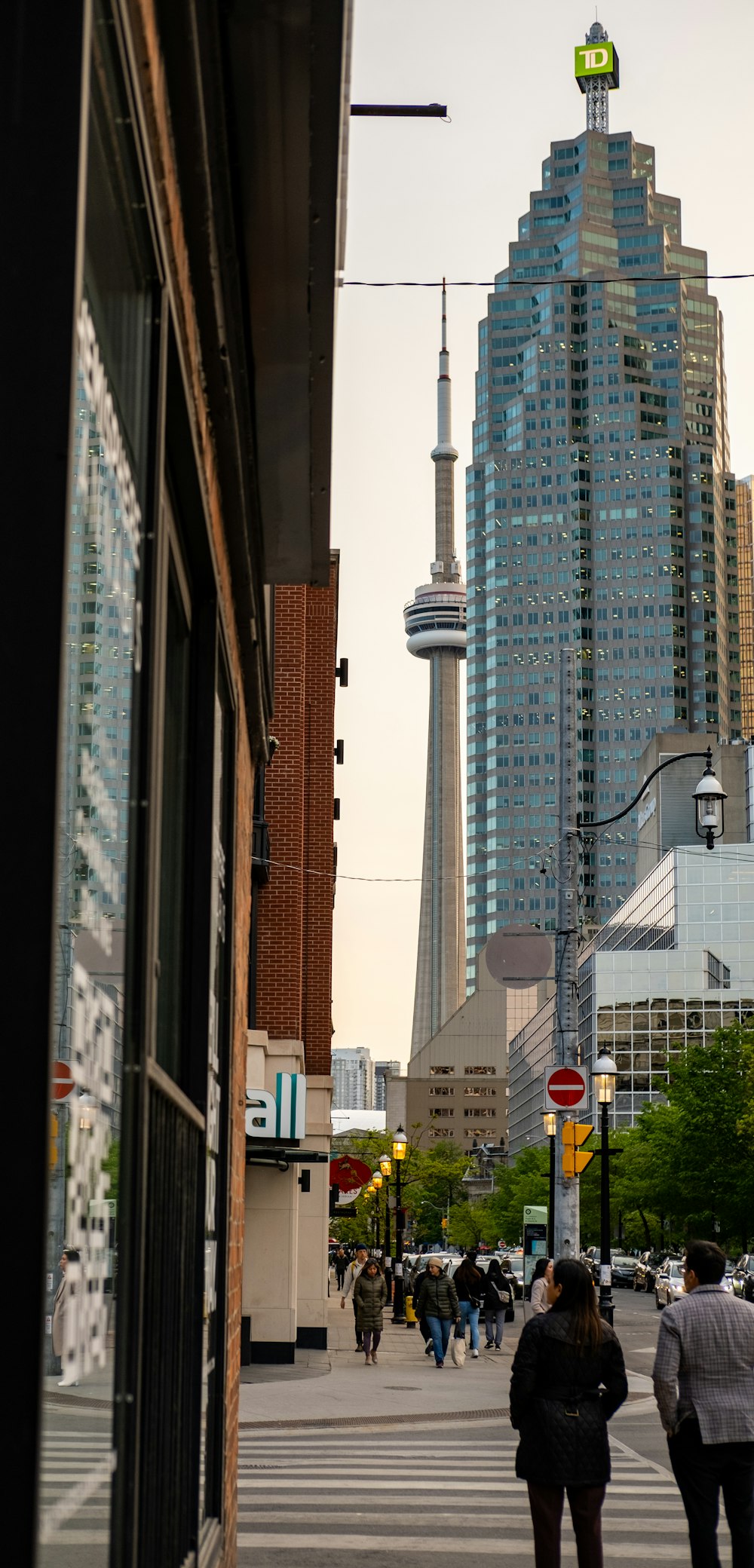 two people walking down a street in front of tall buildings