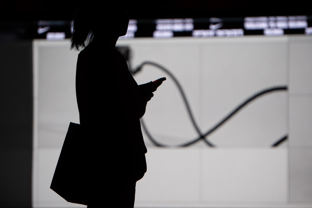 a silhouette of a woman holding a cell phone