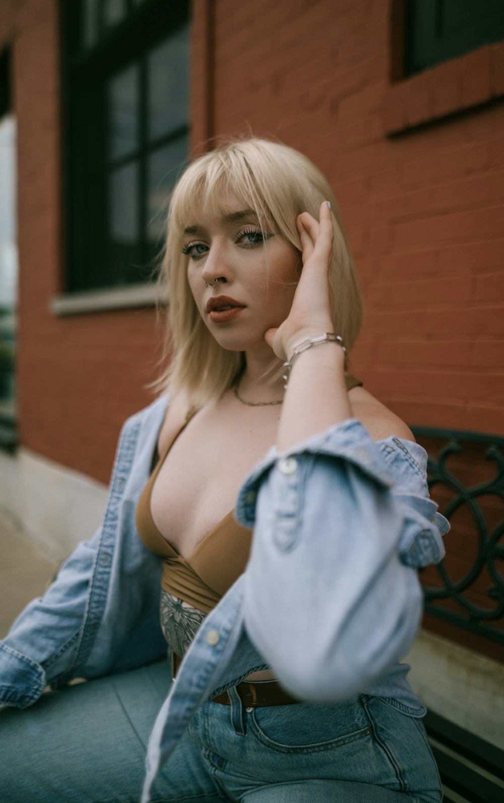 a woman sitting on a bench wearing a jean jacket