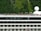 A large cruise ship with multiple decks is shown, featuring people standing on one of the upper decks. The background consists of dense, green forested hills. The top of the ship has circular white structures, and the decks have reflective glass and railings.