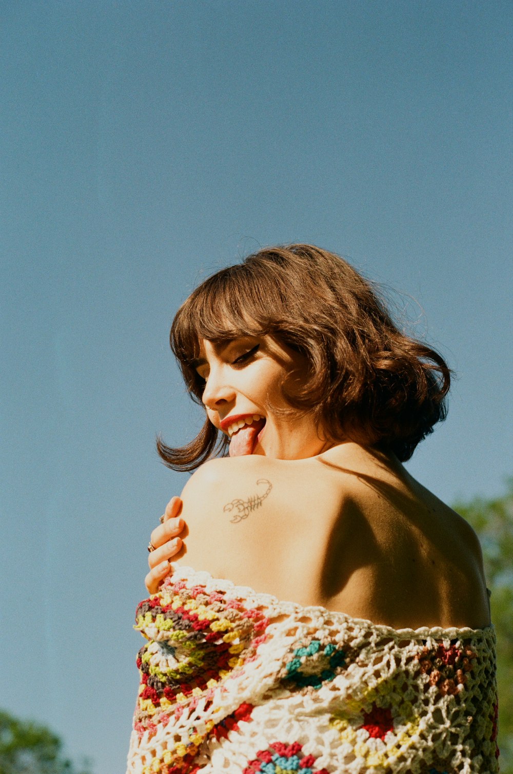 a woman in a crocheted top smiles at the camera
