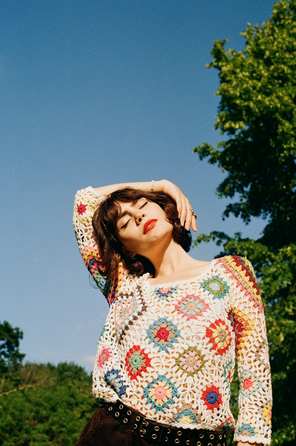 a woman in a crochet top poses for a picture