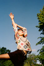 A person stretching outdoors in comfortable workout clothes with a bright morning sky.