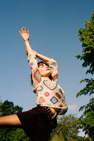 A vibrant, dynamic photo of a woman stretching outdoors wearing colorful, comfortable leggings.