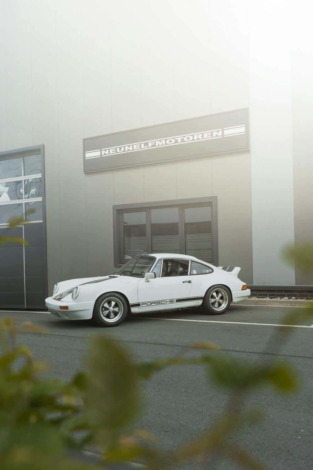 a white porsche parked in front of a building