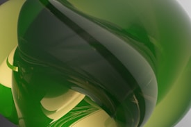 A complex abstract composition featuring intertwining, smooth, glass-like shapes with reflective surfaces. Predominantly green hues dominate the scene, creating a sense of depth and fluidity.