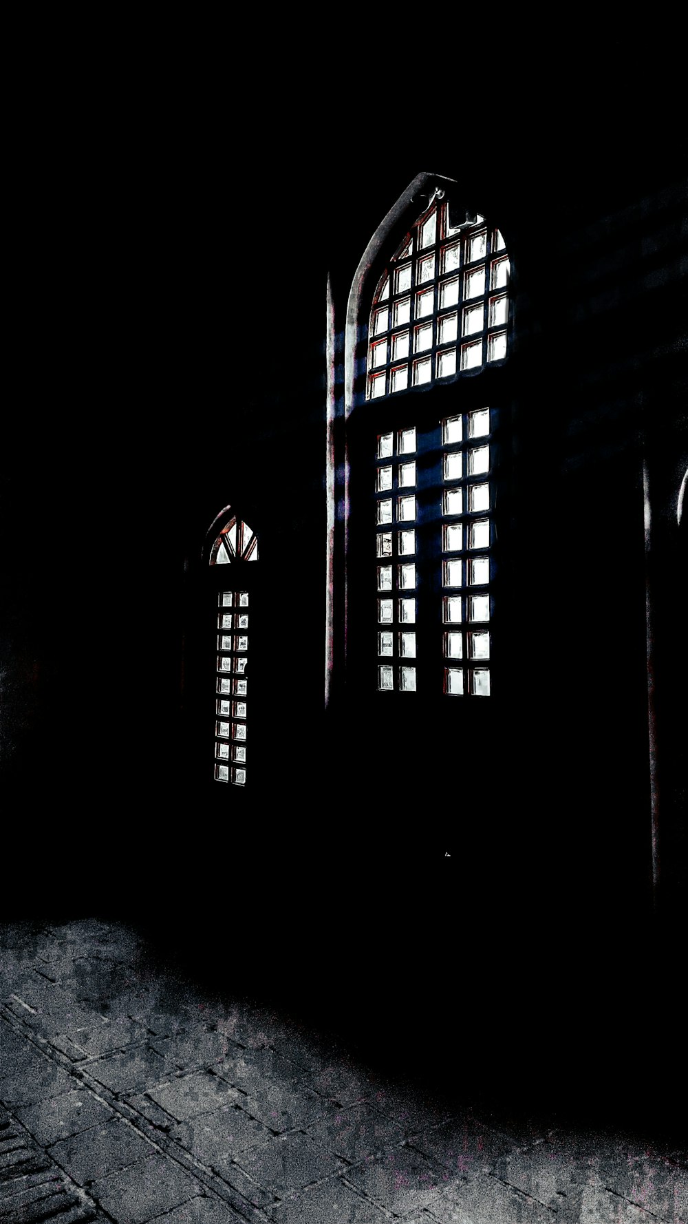 a dark room with three windows and a clock on the wall