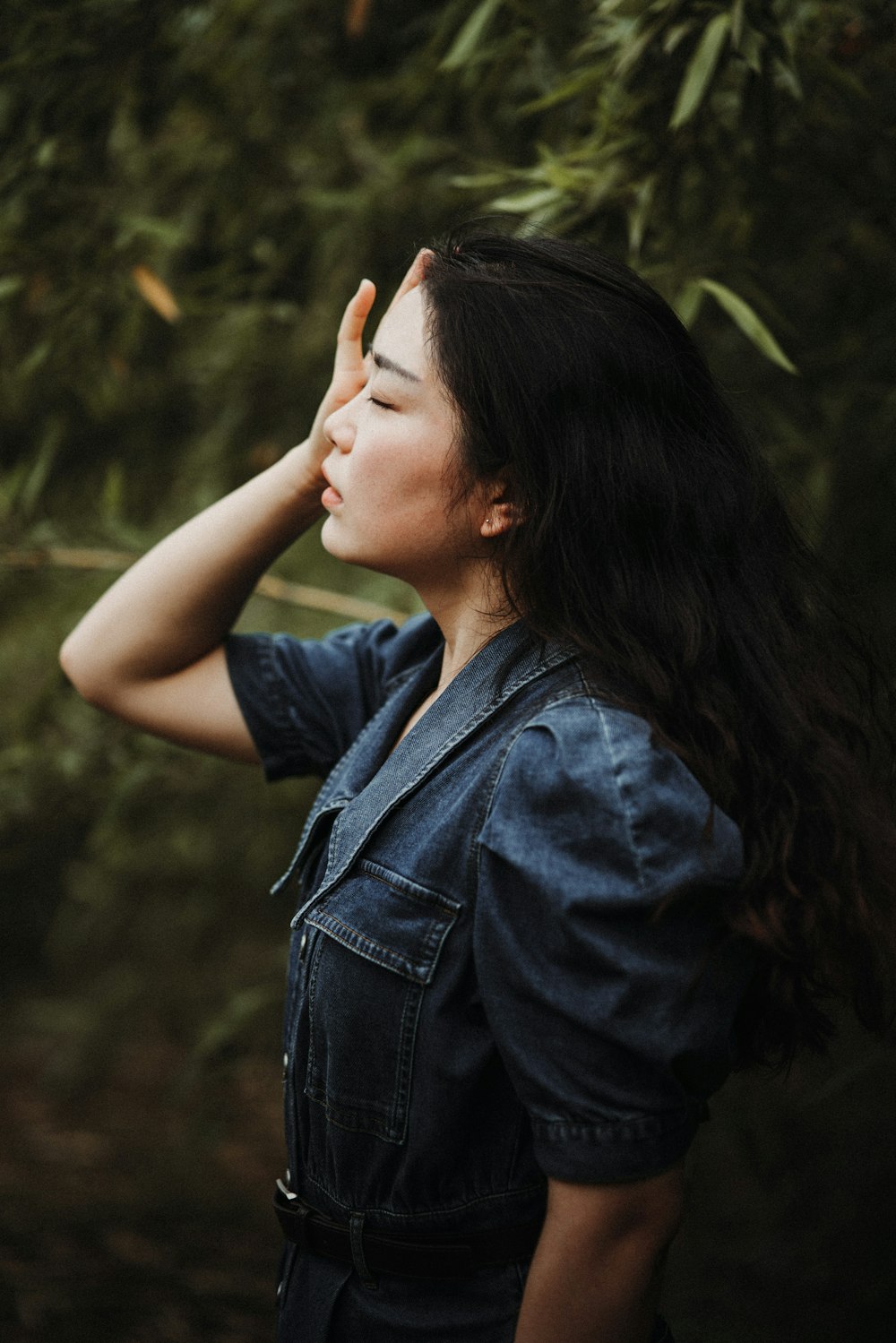 a woman standing in front of a tree with her eyes closed