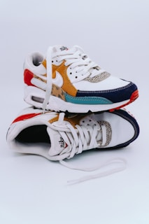A pair of stylish, multicolored sneakers with a mix of materials, including fabric and leather. The shoes feature shades of white, yellow, red, blue, and leopard print accents, along with the Nike logo. They appear to be new and are placed against a plain, white background.