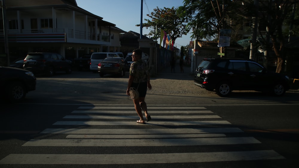 a man walking across a cross walk in the middle of a street