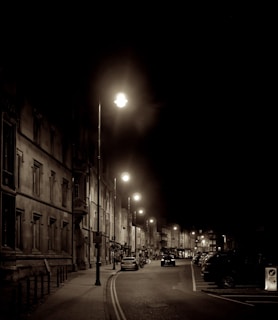 A sepia-toned photo of a bustling 1920s street scene with people and vintage cars.