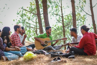 a group of people sitting on the ground playing guitar
