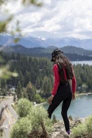 Close-up of a woman stretching in colorful leggings and a lightweight hoodie on a mountain overlook.