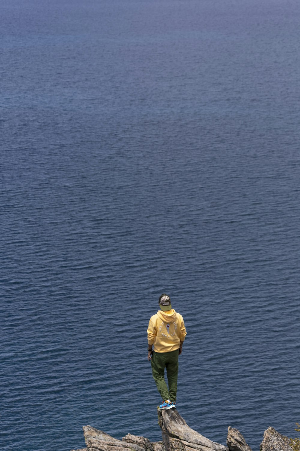 a man standing on top of a rock next to a body of water