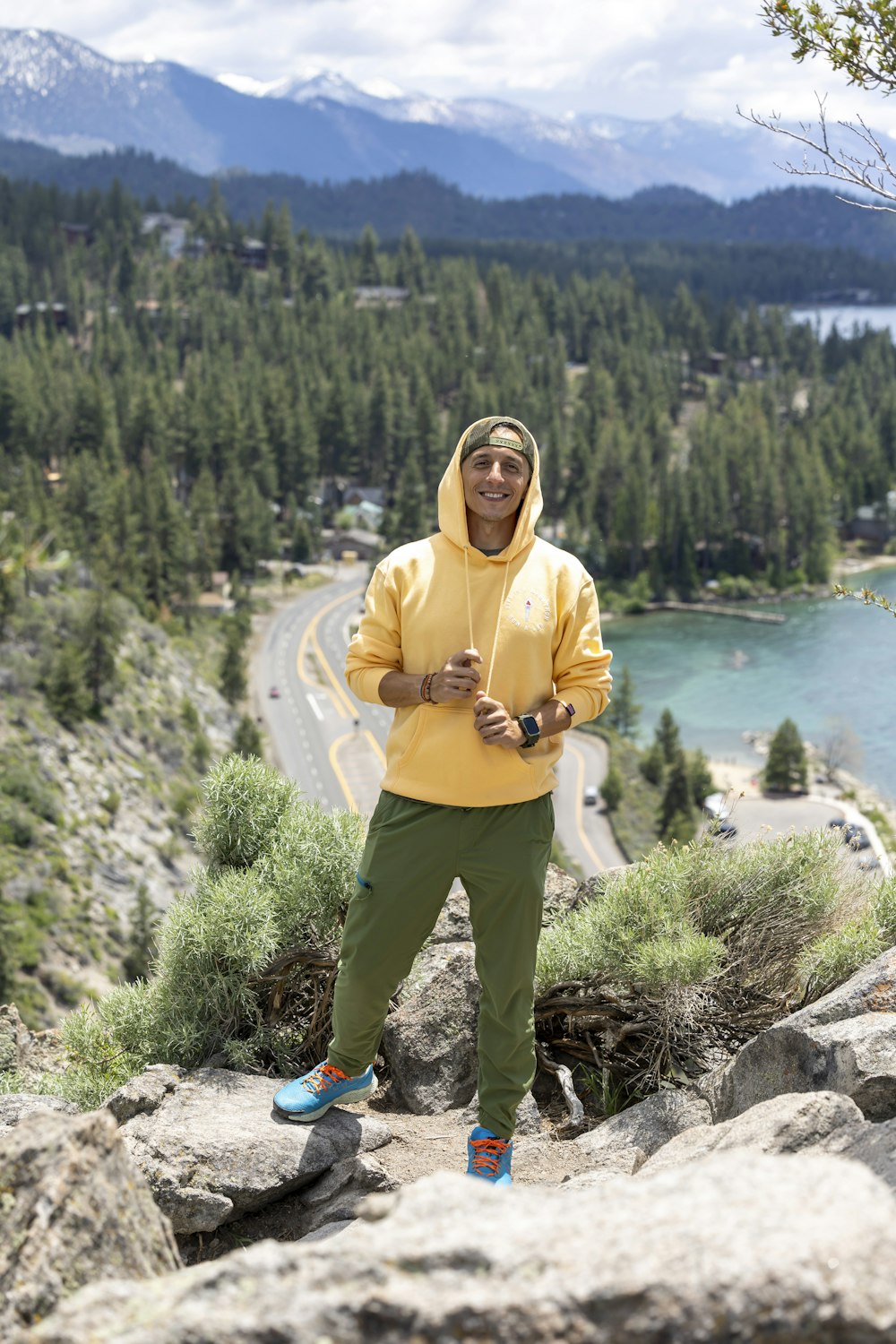 a man in a yellow hoodie standing on a mountain