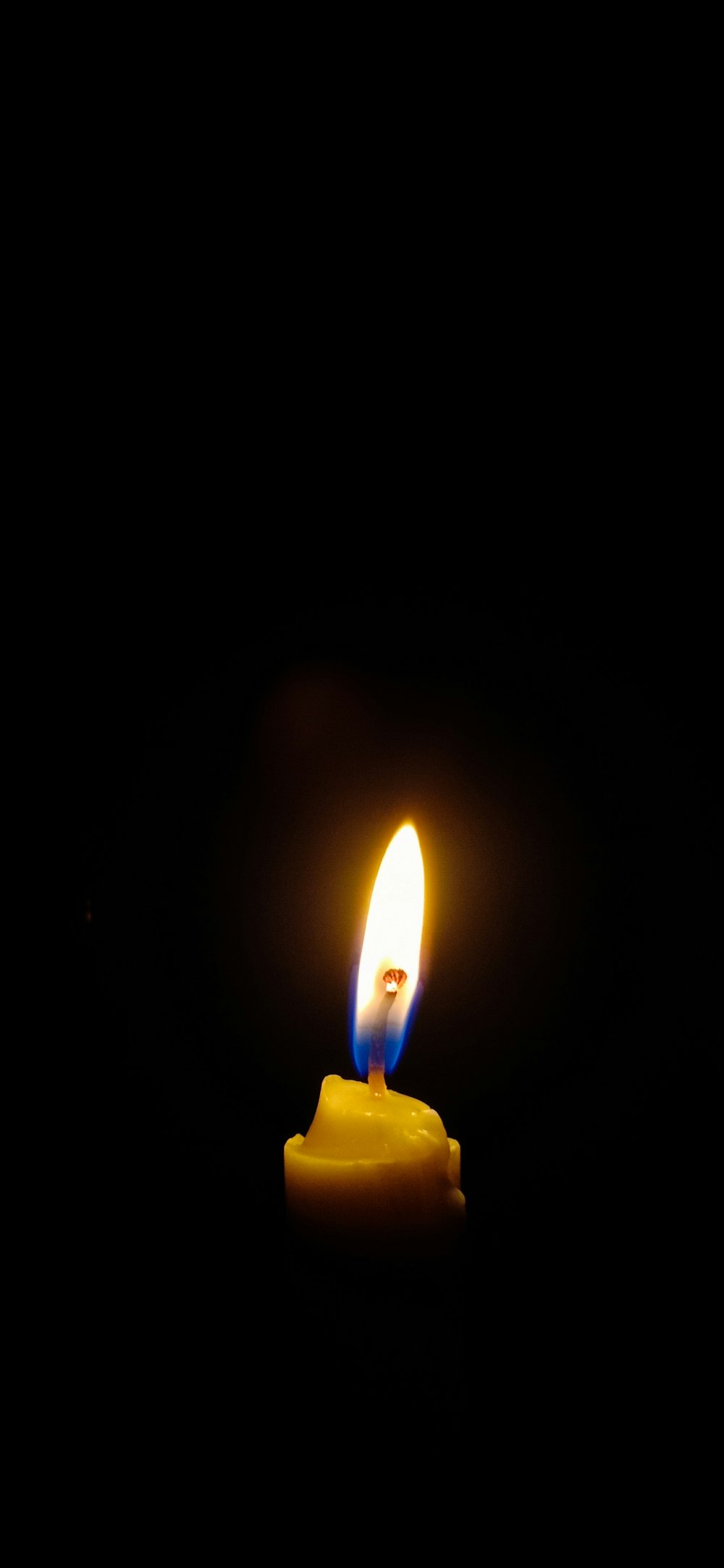 a lit candle in the dark with a black background